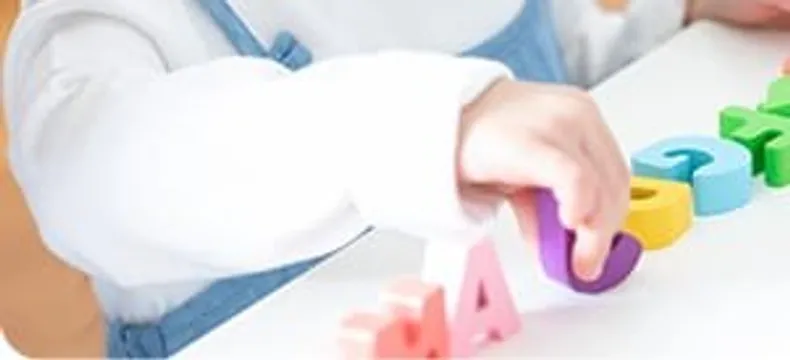アルファベットの積み木で遊ぶ子どもの手元