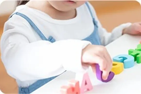 アルファベットの積み木で遊ぶ子どもの手元